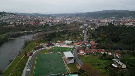 Rio-Miño-and-Oira-soccer-field-in-Ourense,-Galicia,-Spain-panoramic-aerial-establishing-city