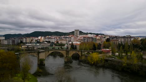 Toma-De-Drone-Del-Puente-Romano-De-Ourense-Cruza-El-Río-En-Ourense,-Galicia,-España
