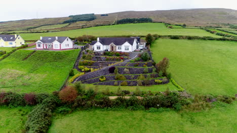 Drone-shot-of-houses-surrounded-by-the-lush-green-fields-of-Donegal,-Ireland