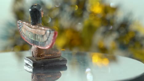 Dreamy-close-up-shot-of-a-Cleopatra-statue-with-wide-open-wings,-hazy-golden-depth-of-field,-ancient,-Egyptian-historical-ruler,-antique-artwork-of-a-goddess,-rotating-360-slow-4K-video-pan-right