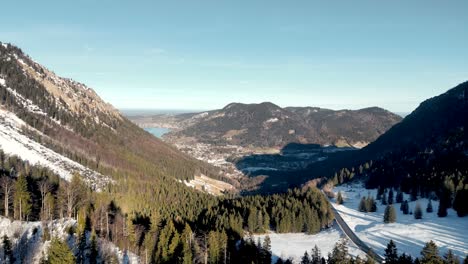Atemberaubende-Luftdrohnenansicht:-Schneebedeckter-Gebirgspass,-Malerische-Aussicht-Auf-Den-Schliersee-In-Deutschland,-Bayerische-Alpenlandschaft-Mit-Straße-Und-Entfernter-Bergsee-In-Der-Wintersaison
