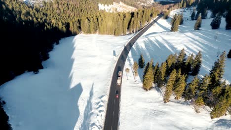 Aerial-Drone-Footage:-Lorry-Truck-Transporting-Huge-Tree-Trunks-over-snowy-Mountain-Pass-in-Bavarian-Alps,-Germany,-Forestry-Industry-Scene-exporting-commercial-goods
