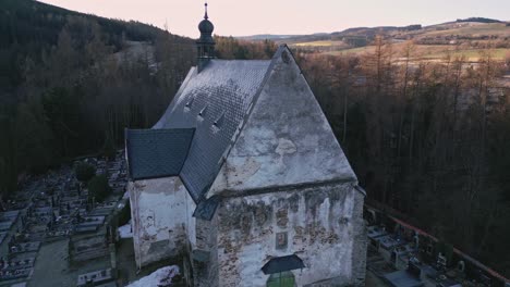 Aerial-view-of-the-gothic-church-in-Velhartice-and-the-surrounding-sunlit-hilly-landscape