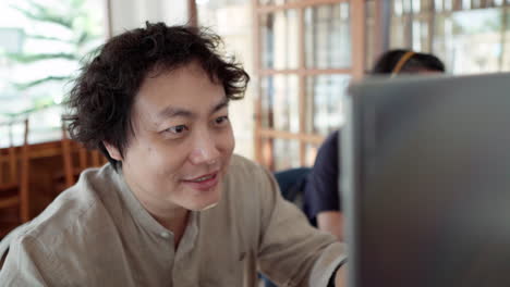 Hombre-Asiático-Sonriente-Trabajando-Con-Una-Computadora-Portátil-En-El-Café