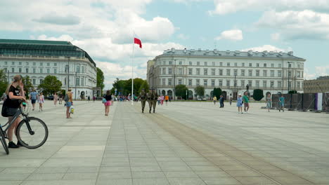 Lively-atmosphere-in-a-Warsaw-city-Pilsudskiego-square,-with-a-backdrop-of-stately-buildings-and-the-national-flag