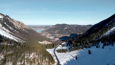 Breathtaking-Aerial-Drone-View:-Snow-covered-Mountain-Pass,-scenic-Schliersee-view-in-Germany,-Bavarian-Alps-Landscape-wit-road-and-Distant-Mountain-Lake-in-the-winter-season