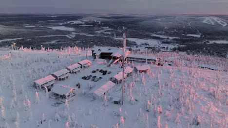 Aerial-view-orbiting-the-Hotelli-Iso-Syöte-resort,-on-top-of-Syote,-sunrise-in-Finland