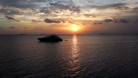 Aerial-view-of-a-modern-live-aboard-dive-ship-moored-at-sunset-in-Dhangethi-Lagoon-with-a-sea-plane-passing
