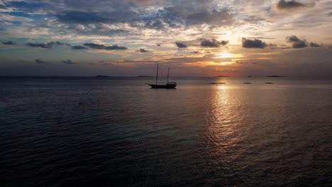 Aerial-view-of-a-masted-sailing-ship-at-sunset-moored-in-Dhangethi-Lagoon,-Maldives,-Indian-Ocean