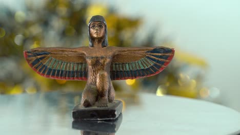 Dreamy-close-up-shot-of-a-Cleopatra-statue-with-wide-open-wings,-hazy-golden-depth-of-field,-ancient,-Egyptian-historical-ruler,-antique-artwork-of-a-goddess,-rotating-360-cinematic-4K-video-pan-right
