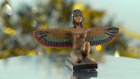 Epic-close-up-shot-of-a-Cleopatra-statue-with-wide-open-wings,-shiny-golden-depth-of-field,-ancient,-Egyptian-historical-ruler,-antique-artwork-of-a-goddess,-rotating-360-smooth-4K-video-tilt-down