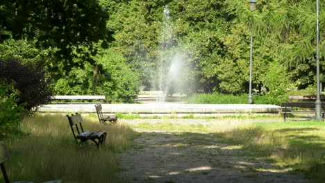 Un-Tranquilo-Rincón-Del-Parque-En-Varsovia-Con-Un-Banco-Y-Una-Suave-Fuente-Entre-árboles