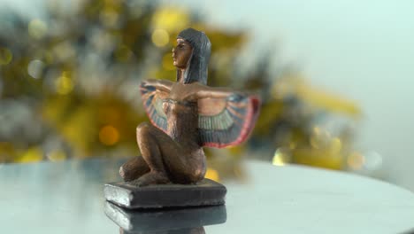 Dreamy-shot-of-a-Cleopatra-statue-with-wide-open-wings,-hazy-golden-depth-of-field,-ancient-Egypt-Queen-of-Kings,-Egyptian-historical-ruler,-antique-artwork-of-a-goddess,-rotating-360-smooth-4K-video