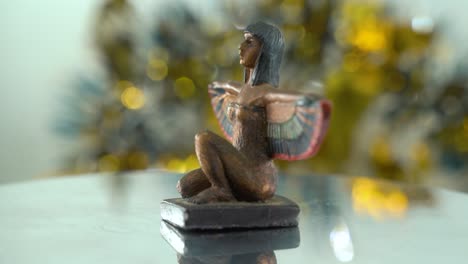 Dreamy-close-up-shot-of-a-Cleopatra-statue-with-wide-open-wings,-shiny-golden-depth-of-field,-ancient,-Egyptian-historical-ruler,-antique-artwork-of-a-goddess,-rotating-360-smooth-4K-video-tilt-down