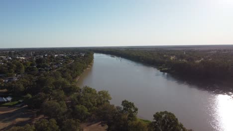Luftaufnahme-Eines-Flusses-In-Australien-Mit-Einer-Kleinen-Stadt-Auf-Der-Linken-Seite-Und-Einer-Riesigen,-Belebten-Seite-Auf-Der-Rechten-Seite