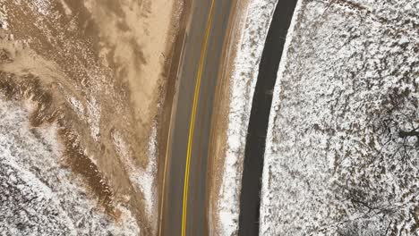 Direct-aerial-of-a-coastal-road-with-snow-and-sand