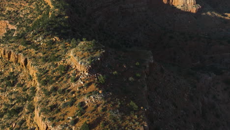 Aerial-view-tilting-over-large-sunlit-cliffs,-warm,-sunny-evening-in-Utah,-USA
