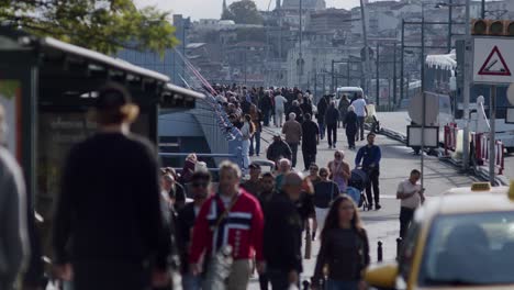 Crowd-of-people-walking-on-the-streets-of-Istanbul,-People-fishing-on-Galata-bridge-in-the-background