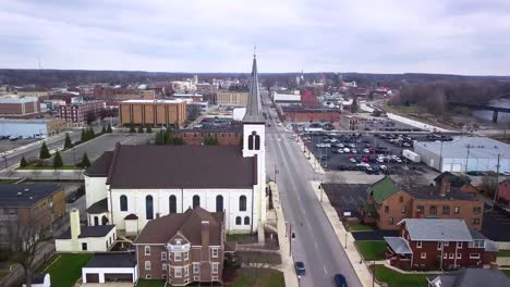 Aerial-view-flyover-Logansport-small-white-church-with-steeple-in-downtown-Indiana-townscape
