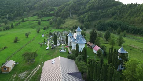 Flying-Towards-Medieval-Church-With-A-Graveyard-In-Palanca-Town,-Bacau-County,-Western-Moldavia,-Romania