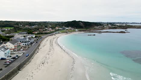 Vuelo-De-Cobo-Bay-Guernsey-Sobre-La-Playa-Dorada,-Rocas-Cristalinas-Y-Paseo-Marítimo,-Incluido-El-Hotel-Rockmount-Y-Cobo-Bay-En-Un-Día-Tranquilo-Y-Soleado