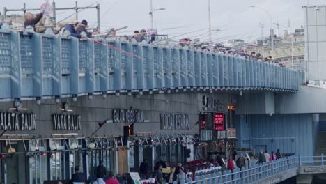Panoramablick-Auf-Menschen,-Die-An-Der-Galata-Brücke-Angeln,-Mit-Blick-Auf-Das-Berühmte-Türkische-Fischrestaurant