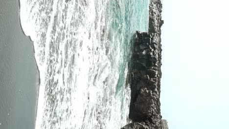 Waves-hitting-black-volcanic-sand-beach-in-Tenerife,-vertical-view