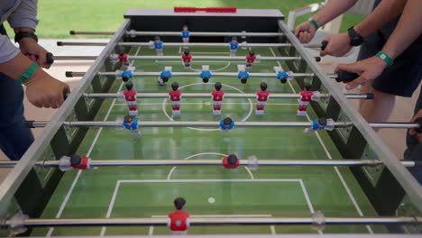 foosball-competition-between-young-men-in-the-hall-insert-shot,-push-in-shot,-push-out-shot