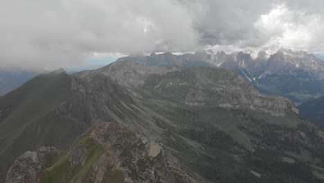 Drone-gliding-through-clouds-over-the-Monzoni-Ridge,-Catinaccio-Dolomites-visible-in-the-background