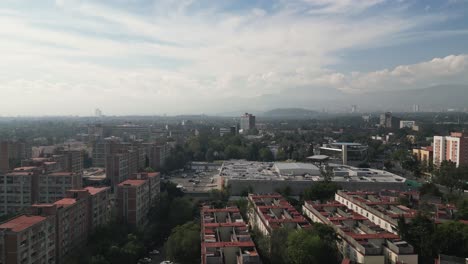 Taking-flight-drone-ascends,-revealing-the-southern-expanse-of-Mexico-City,-with-the-iconic-Ciudad-Universitaria-gracing-the-background
