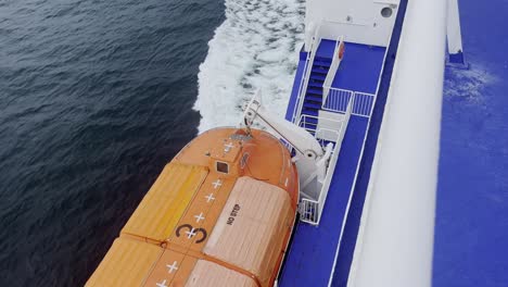 Orangefarbenes-Rettungsboot-Auf-Einer-Fähre,-Die-Auf-Dem-Meer-Mit-Blauen-Und-Weißen-Geländern-Auf-Dem-Weg-Nach-Schweden-In-Europa-Schwimmt