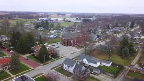 Aerial-view-over-Sheridan-town-autumnal-neighbourhood-in-Hamilton-county-Indiana-towards-Methodist-church