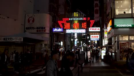Dotonbori-Entertainment-District-At-Night-With-Illuminated-Road-Sign-With-People-Walking-Past