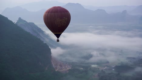 Vista-Aérea-De-Un-Globo-Aerostático-Sobre-Las-Nubes-Sobre-El-Suelo-Del-Valle-De-Vang-Vieng-En-Laos.