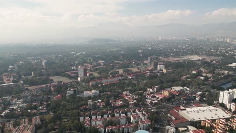 Drone-taking-off-with-a-view-of-the-south-of-Mexico-City,-with-Ciudad-Universitaria-in-the-background