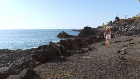 Mujer-Joven-Caminando-Junto-A-La-Costa-De-Tenerife,-Vista-Posterior