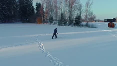 Drone-shot-of-a-cross-country-skier-approaching-a-sauna-in-Latvia