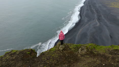 A-Woman-Standing-Over-Promontory-Of-Dyrholaey-Viewpoint-In-Iceland