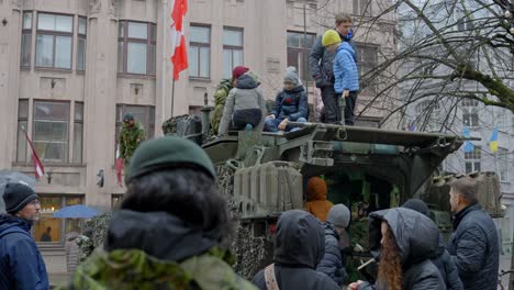 Desfile-Militar,-Civiles-Mirando-El-Vehículo-Lav-6-Con-Soldados-Alrededor,-Riga