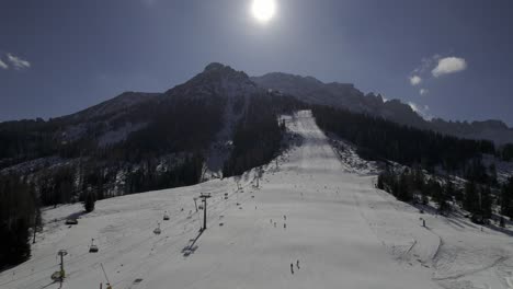 Drohnenaufnahme-Im-Skigebiet-Carezza-Im-Winter,-Die-Die-Schneebedeckte-Piste-Pra-Dei-Tori-Zeigt,-Während-Skifahrer-Ihren-Weg-Nach-Unten-Bahnen