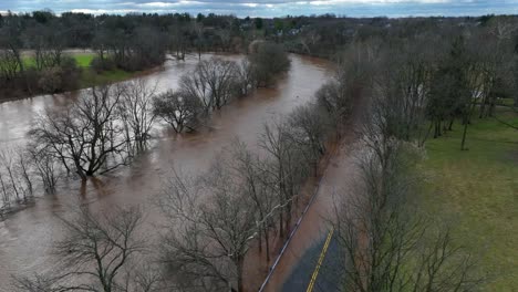 Aerial-flyover-flooded-Conestoga-River-after-strong-rain-in-Lancaster-during-cloudy-day,-Usa---Environmental-catastrophe-on-earth