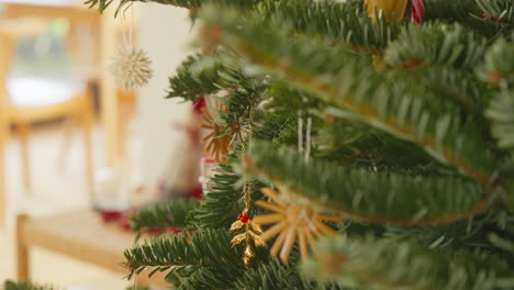 Close-up-of-a-golden-mistletoe-ornament-on-a-festive-Christmas-tree
