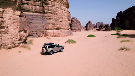 Four-wheel-Drive-Vehicle-Driving-Through-Sahara-Desert-In-Tassili-n'Ajjer-National-Park-At-Midday-In-Algeria