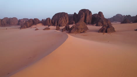Sand-Dunes-At-Sahara-Desert-With-Sandstones-In-The-Background-At-Sunrise-In-Tassili-n'Ajjer-National-Park,-Algeria