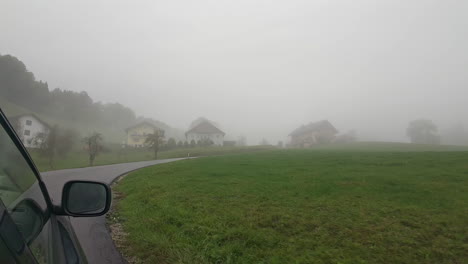 Lone-driver-travels-down-a-foggy-road,-approaching-a-town-shrouded-in-mystery