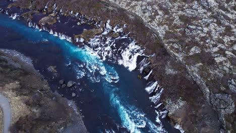 Cinematic-drone-establisher-of-impressive-waterfall-Hraunfossar-in-Iceland,-aerial-orbit