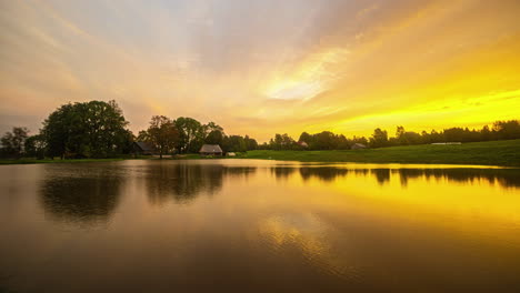 Timelapse-shot-of-a-cloud-movement-over-a-cottage-beside-a-lake-along-rural-countryside-throughout-the-day