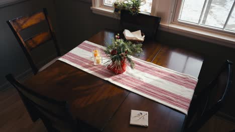 push-in-shot-of-a-kitchen-table-with-a-christmas-decoration-on-top-along-with-a-red-and-white-table-cloth