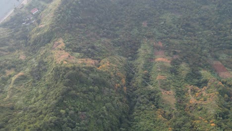 Vista-De-Drones-En-Guatemala-Volando-Sobre-Un-Bosque-Verde-Y-Mostrando-Una-Ciudad-Rodeada-Por-El-Lago-Y-Las-Montañas-En-Un-Día-Nublado-En-Atitlán