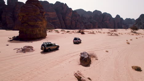 Off-road-SUV's-Driving-Through-The-Desert-Along-The-Sandstone-Formation-In-Tassili-n'Ajjer-National-Park,-Algeria